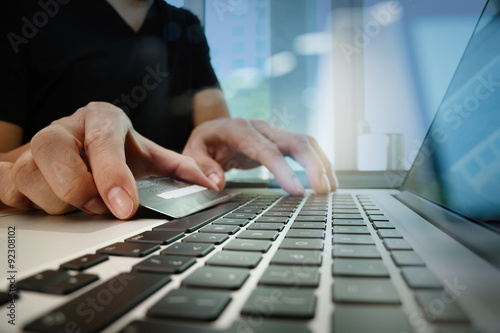 close up of hands using laptop and holding credit card as Online