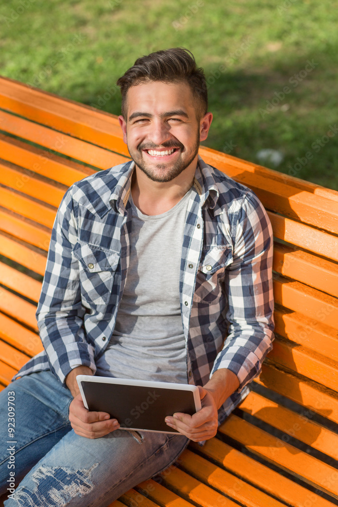 Fototapeta premium Young man working on tablet PC outdoors