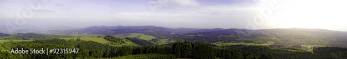 Panorama with hills, forests, sky and sun shine