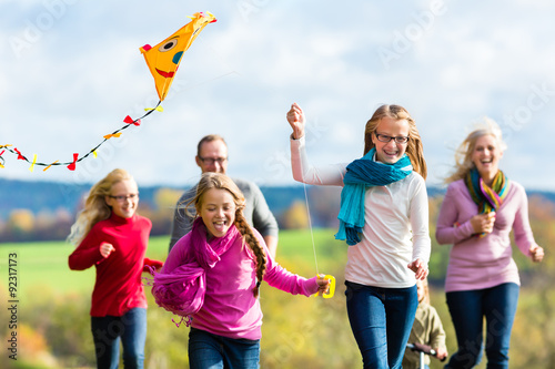 Mädchen rennen und lassen Drachen steigen bei Familien Spaziergang im Herbst Park vorweg photo