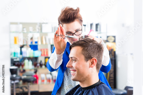 Hairdresser cutting man hair in barbershop