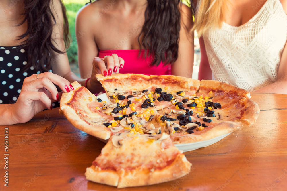 Anonymous female friends sharing a pizza