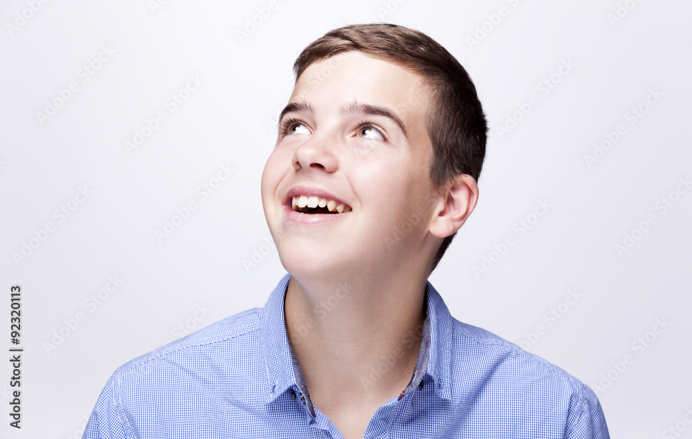 Daydreaming boy looking up against grey background Daydreaming boy looking up against grey background