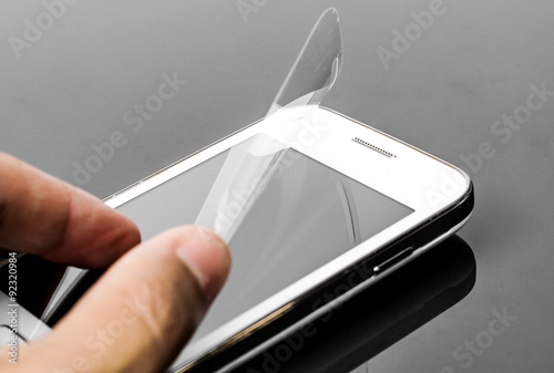 Quadro em tela hand laying scratch protective film on a smartphone