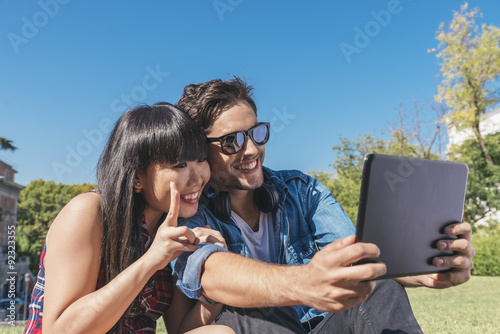 Young happy couple using tablet in the park