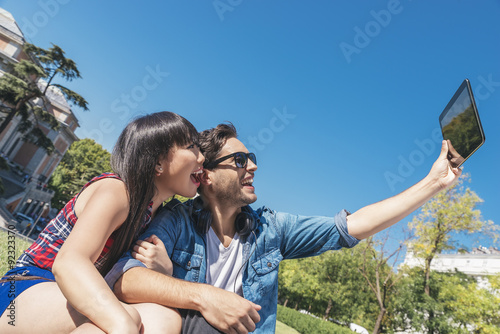 Young happy couple using tablet in the park