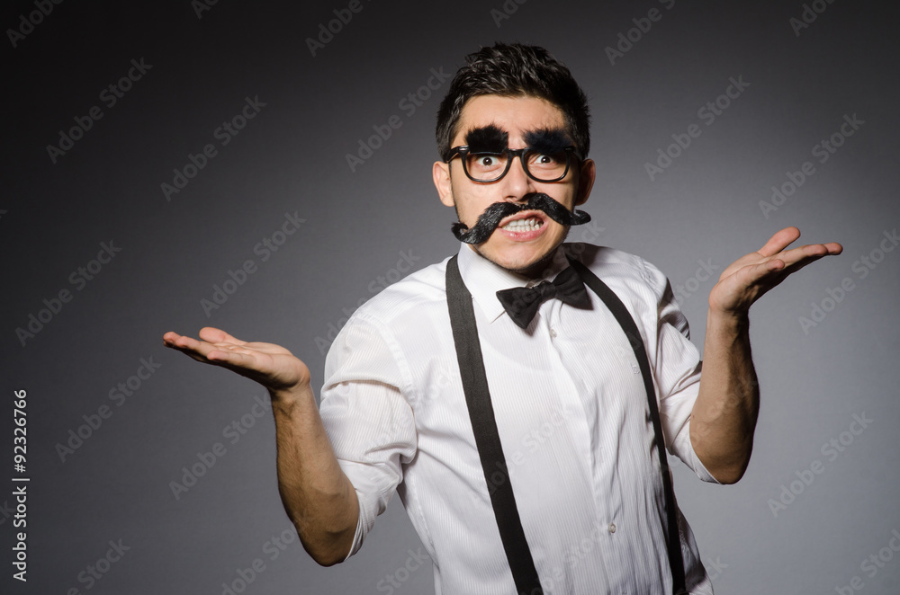 Young caucasian man with false moustache against gray Young caucasian man with false moustache against gray