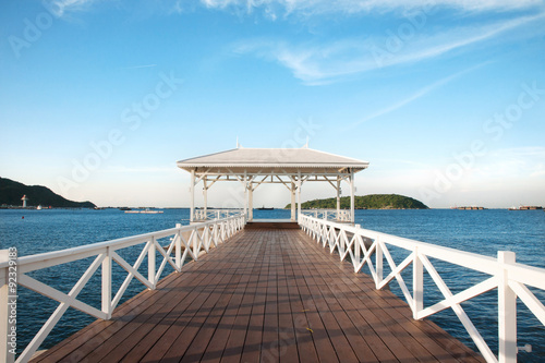 Fototapeta Naklejka Na Ścianę i Meble -  Beautiful white wooden bridge laying toward the sea with blue sky at the beach in Thailand.