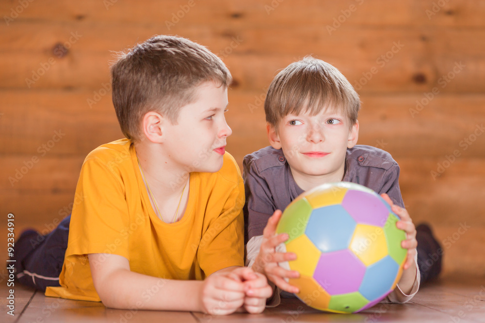 Fototapeta premium Two friends with a ball lying on the floor