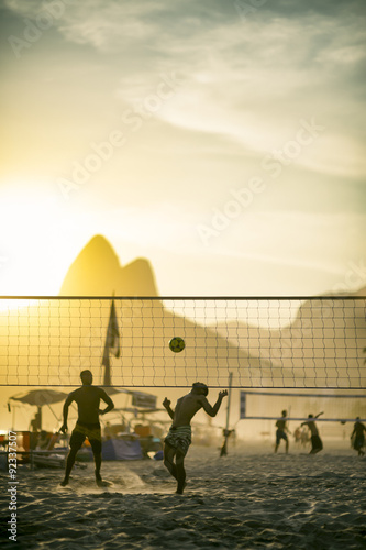 Silhouettes of Brazilians playing a beach ball game in the sand between volleyball nets against a backdrop of Dois Irmaos Mountain on Ipanema Beach, Rio de Janeiro Brazil 