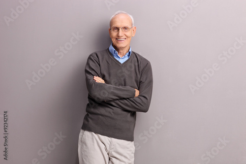Cheerful senior leaning against a gray wall