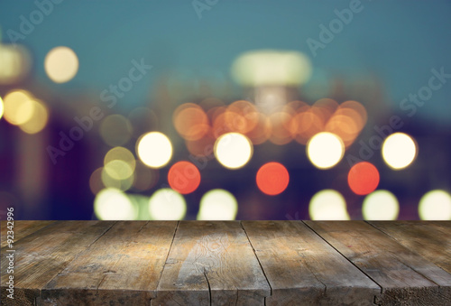 image of wooden table in front of abstract blurred background of city lights

