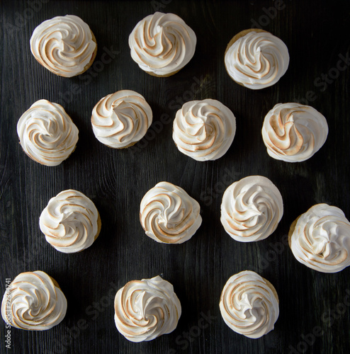 White meringue cookies on a black wooden background