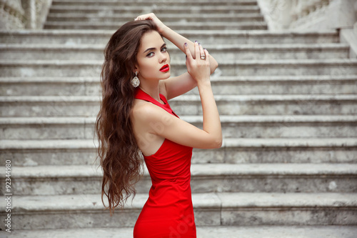 Beautiful brunette girl in red dress with long healthy hair posi