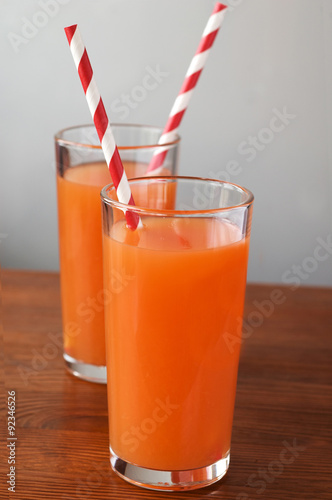 фотографія carrot juice and carrot segments on a wooden background with nat