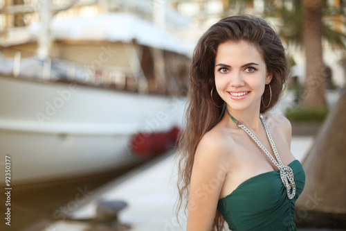 Beautiful teen girl smiling against the boat at sunset, outdoor