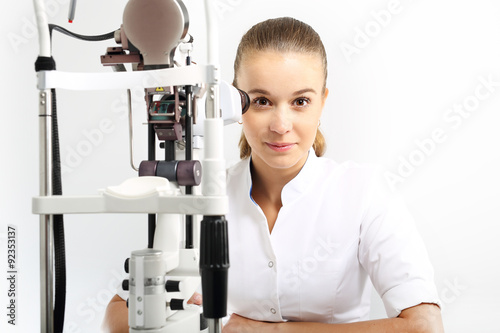 Szpital oddzia   okulistyki  m  oda okulistka siedzi przy maszynie do badania oczu