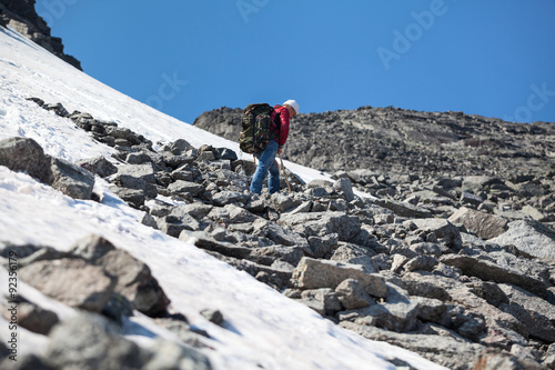 Senior man a mountaineer standing on the stony steep slope in mountains, copy space