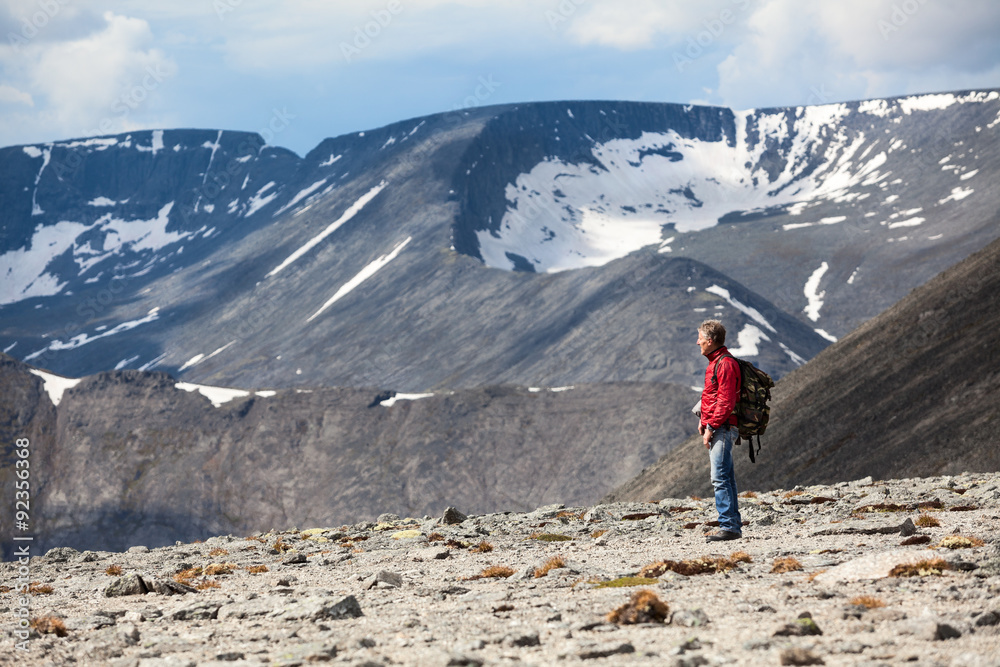 Mature Caucasian hiker looking down at the mountain slope, copy space