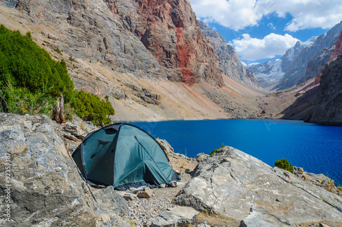 Lonely tent stands on the shore of a beautiful mountain lake