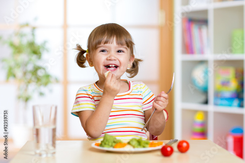 kid girl eating healthy vegetables