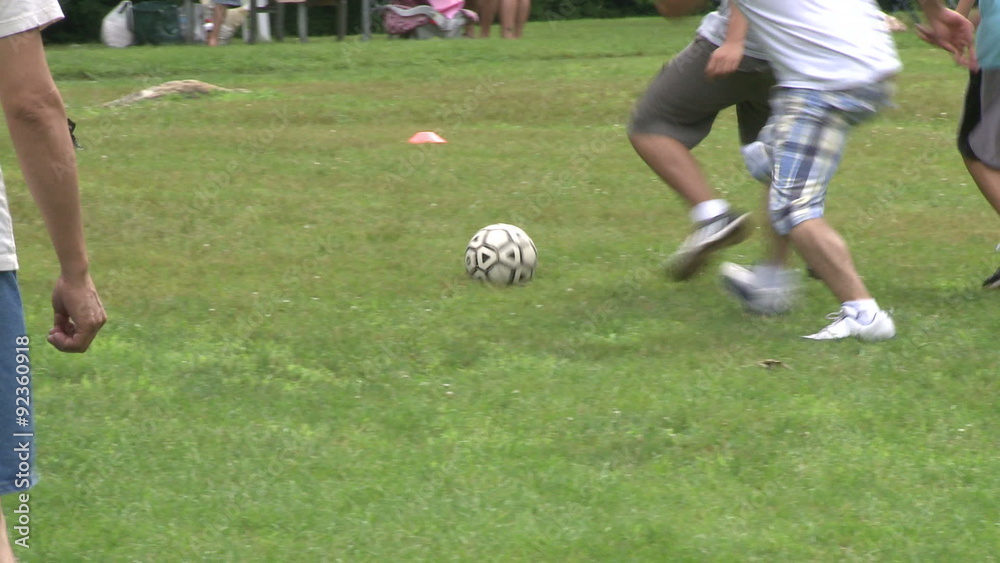 Boys playing soccer in a park at a picnic Boys playing soccer in a park at a picnic