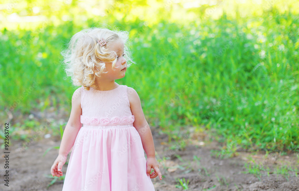 Cute little girl child with curly hair wearing a pink dress in p Cute little girl child with curly hair wearing a pink dress in p