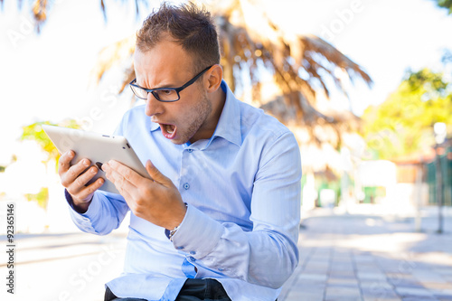 Young tourist in shirt with mobile phone on a Croatian beach. Negative emotions.