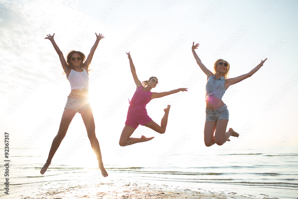 happy female friends dancing and jumping on beach happy female friends dancing and jumping on beach