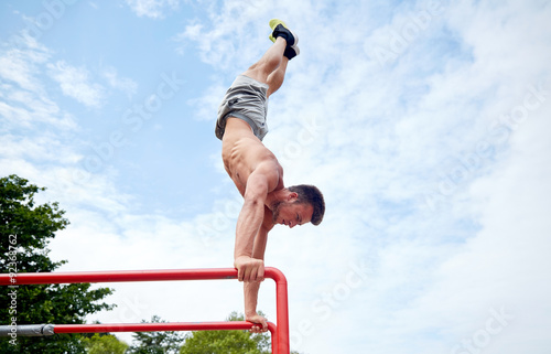 young man exercising on parallel bars outdoors