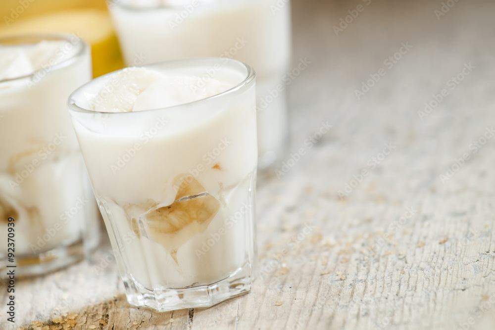 Fresh homemade banana yogurt in glass on old wooden table, selec Fresh homemade banana yogurt in glass on old wooden table, selec