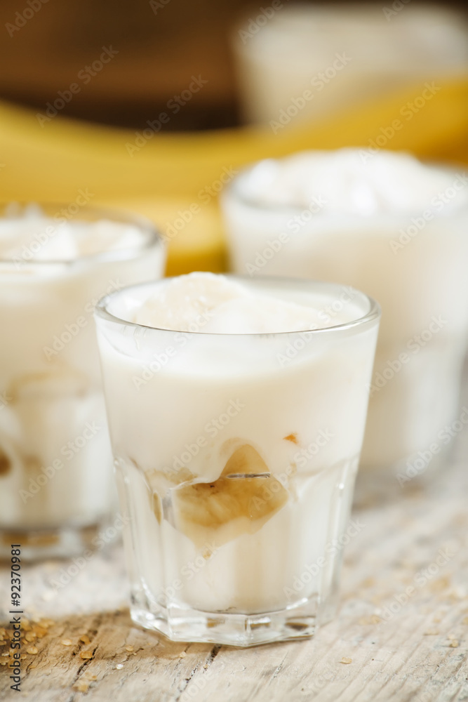 Fresh homemade banana yogurt in glass on old wooden table, selec Fresh homemade banana yogurt in glass on old wooden table, selec