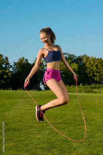 Girl funny jumping on jump rope with a smile. photo