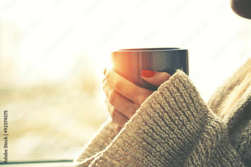 hands holding hot cup of coffee or tea in morning sunlight - obrazy, fototapety, plakaty 