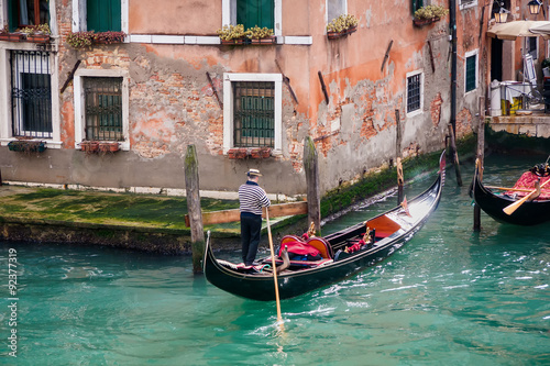 man in gondola in narrow canal with bridge Venice, Italy, Europe