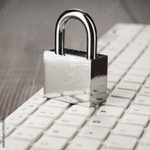 padlock and white computer keyboard on the wooden office table