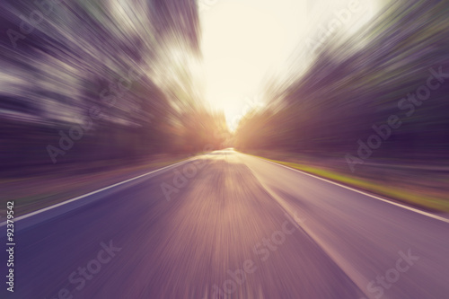 Empty asphalt road in motion blur and sunlight with vintage tone