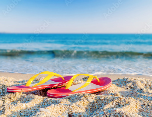 Fototapeta Naklejka Na Ścianę i Meble -  Flip flops on a sandy ocean beach