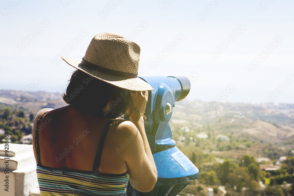 Woman looking at landscape through a telescope. Vintage tone.
