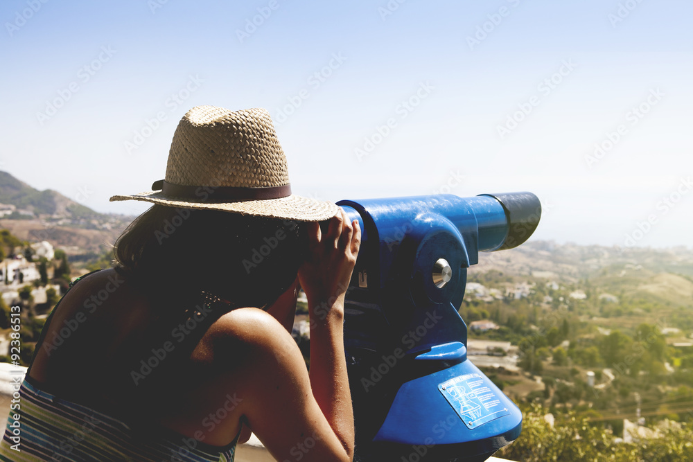 Woman looking at landscape through a telescope. Vintage tone.
