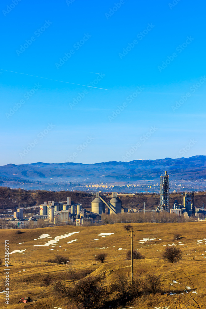 Industrial area in in the background with smoking factory chimneys, forest and mountains,