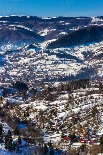 Sunny winter alpine scenery with small Romanian village in the valley of Bucegi