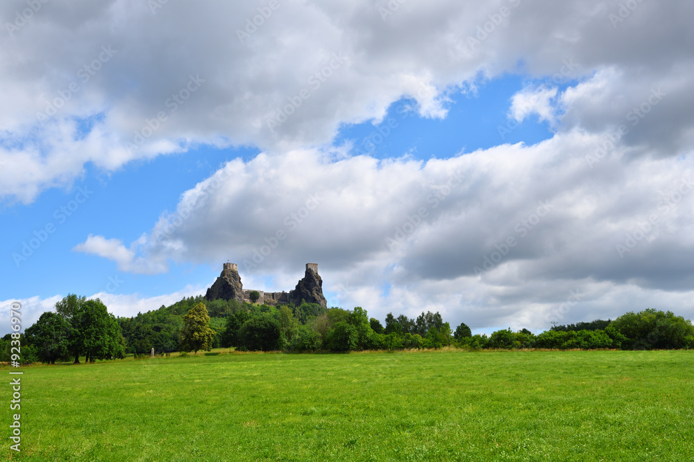 Green grassfield with medieval castle ruins under cloudy sky