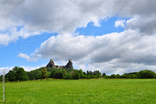 Green grassfield with medieval castle ruins under cloudy sky