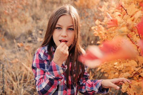 cute thoughtful kid girl in country style shirt eating autumn berry