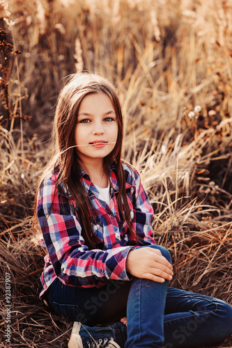 cute smiling kid girl in country style plaid shirt on field