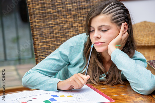 beautiful tired girl student doing her homework with concentration