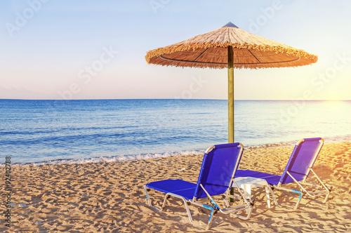 Fototapeta Naklejka Na Ścianę i Meble -  Two blue sunbed, straw umbrella on beautiful beach background