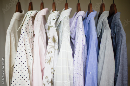 A row of assorted business shirts for women on hangers in a clos