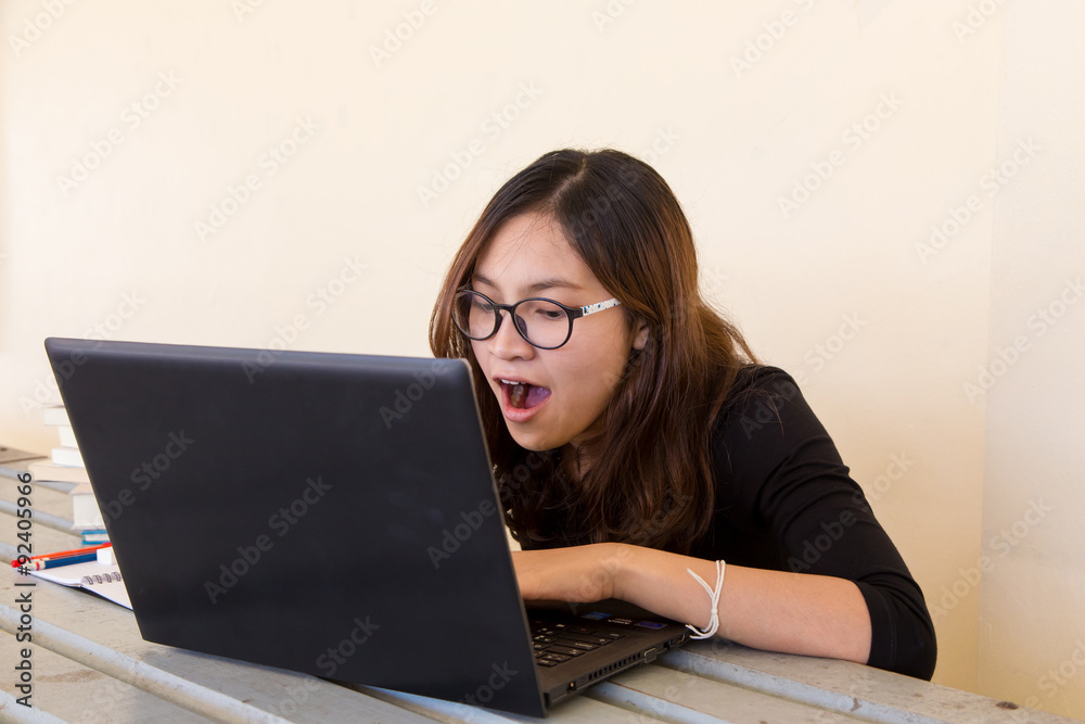 Young woman tired of working, doing homework, with notebook and laptop Young woman tired of working, doing homework, with notebook and laptop